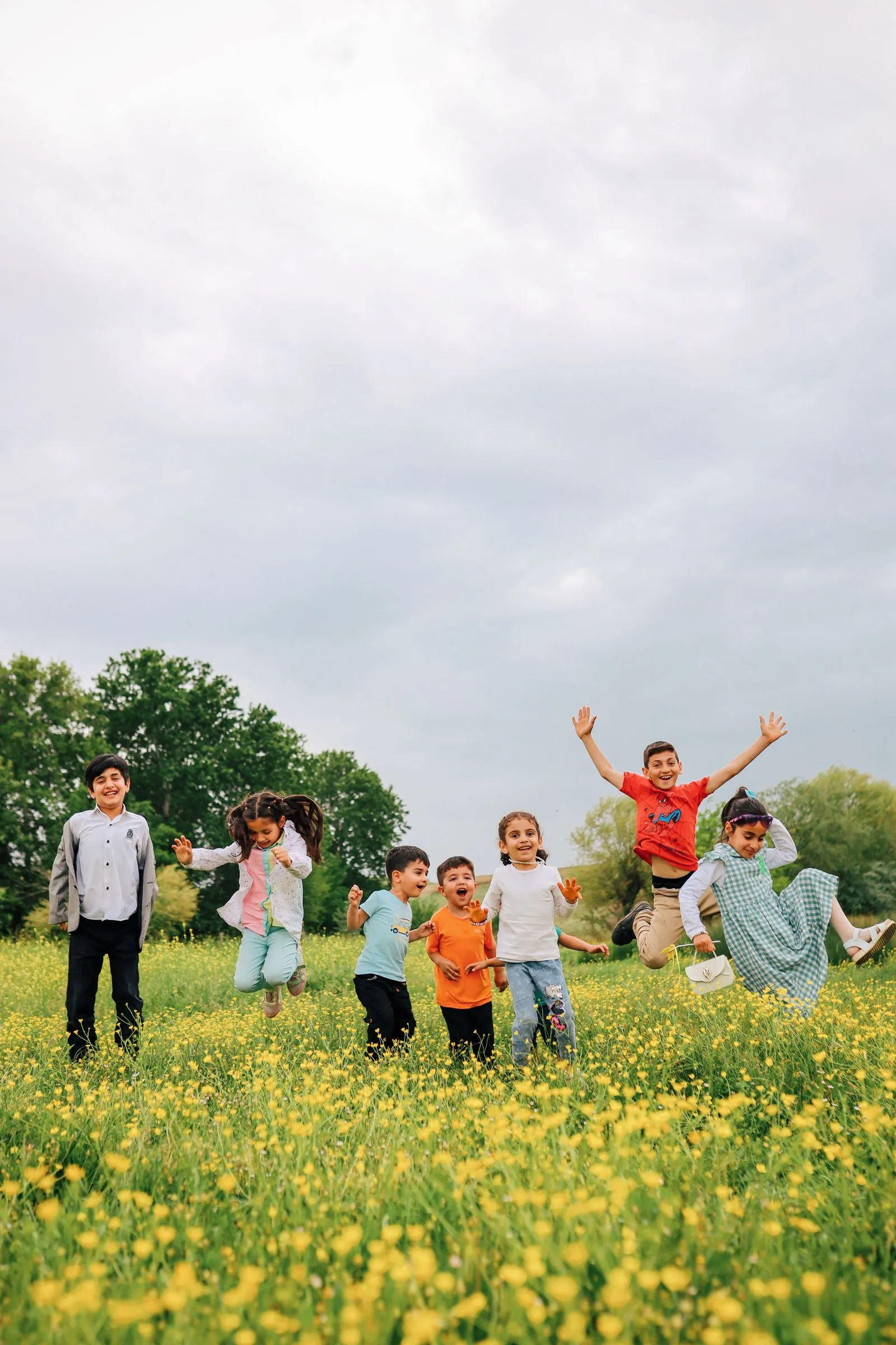 Grup d'infants saltant i jugant en un prat ple de flors un dia d'estiu